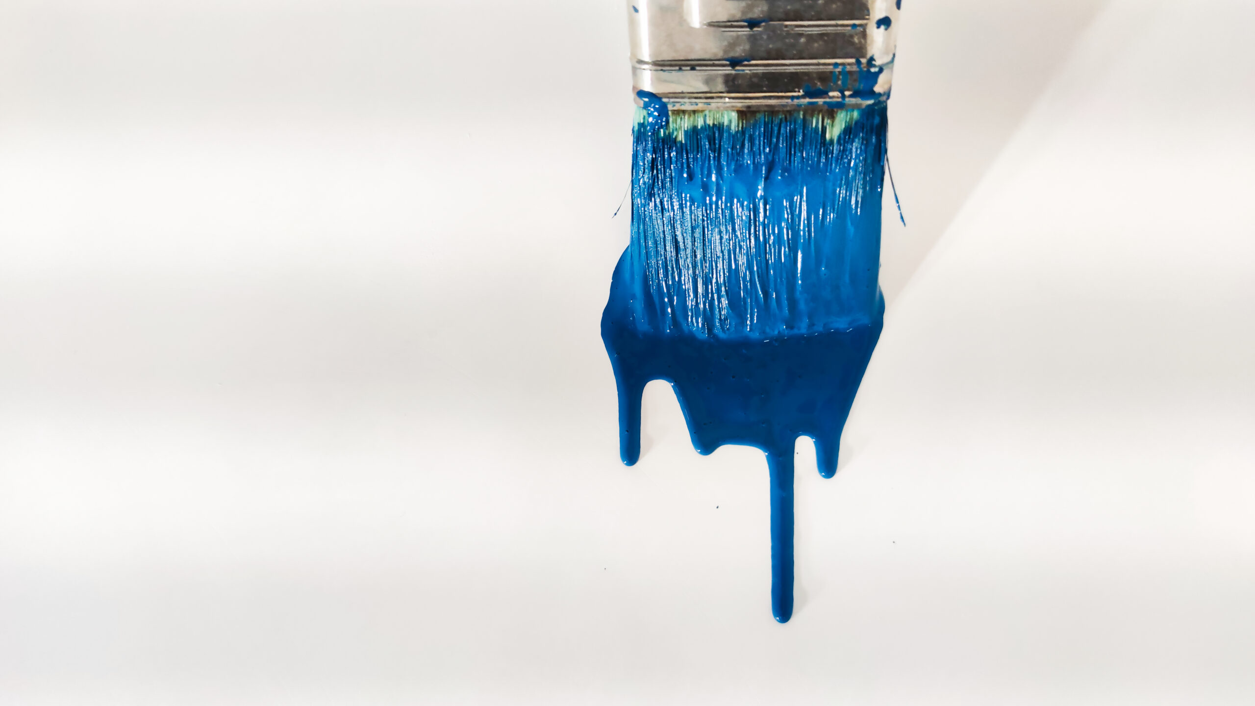 Brush with blue paint on a white background